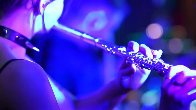 rock musician a girl plays a wind instrument, clarinet or flute on the stage of a rock concert