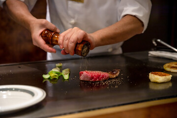 鉄板焼きステーキを料理人が調理している