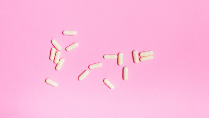 Tablets drugs therapy antibiotic on pastel pink background from above