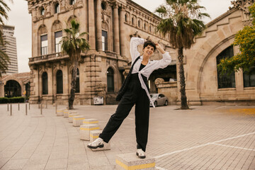 Full length cheerful caucasian young woman walks in european city at weekend. Brunette wears casual clothes for every day. Concept positive attitude