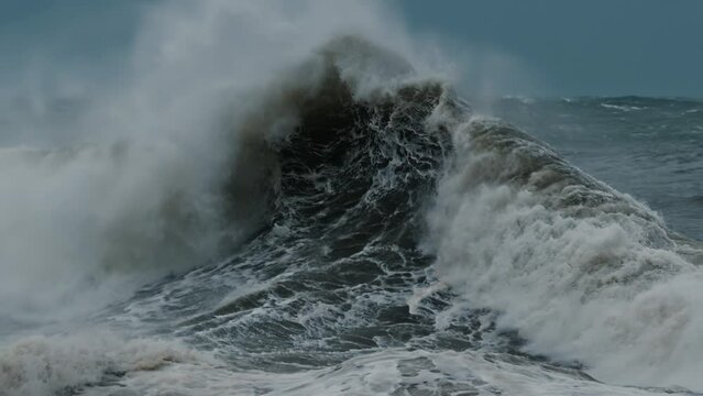 Big wave with foam and dirt breaks on the shore during strong storm in the Atlantic Ocean
