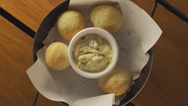 People take chipa rolls from spinning dish, top down view