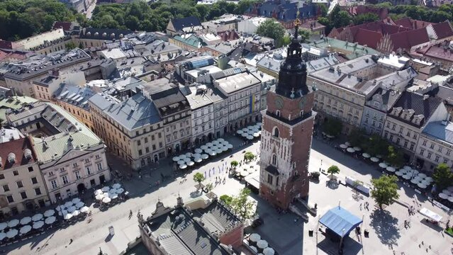 Polish people walk near Town Hall Tower (Wieża Ratuszowa) in the main square. City Centre flyover of Krakow, Poland, a Polish historic capital, with traditional architecture - 4K 30FPS Static