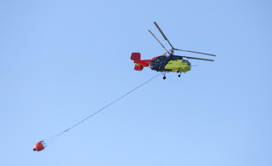 Fototapeta na wymiar Helicopter with water to extinguish a fire