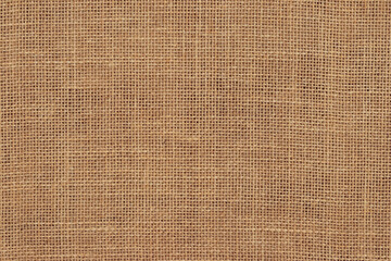 Brown burlap cloth background or sack cloth for packing. Natural linen threads texture. Sackcloth, empty space. Wrapping detail, old grainy cotton backdrop close-up.