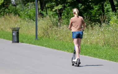 A girl rides a scooter along the road