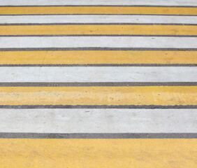 Yellow and white stripes on a pedestrian crossing.