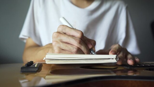 Musician using pen and notebook to write a song