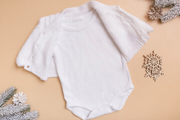 White baby bodysuit mockup for logo, text or design on beige background with winter decotations top view