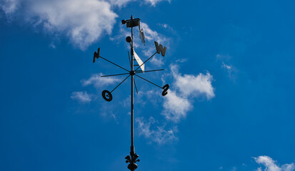 wind rose and weather vane on the blue sky with clouds