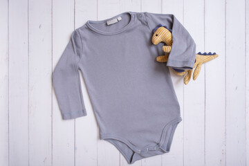 Grey baby bodysuit top view. Mock up for logo, text or design on wooden background. Flat lay with...