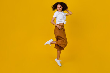 Fototapeta na wymiar Full body photo of excited carefree lady arm touch hair good mood jumping isolated on yellow color background