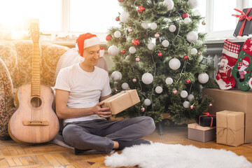 young handsome man sitting on the sofa, he is playing guitar, music, christmas, relax concept