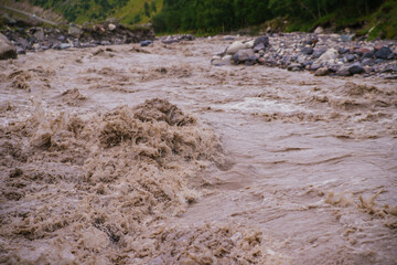 Muddy river water. Spring flood. Dirty muddy water with a whirlpool and white foam close-up.A...