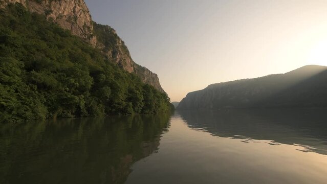 Danube Gorges (Cazanele Dunarii in Romanian language) view from a boat during a beautiful summer sunrise. Cruise on Danube River, 4k video. Landmarks of Romania.