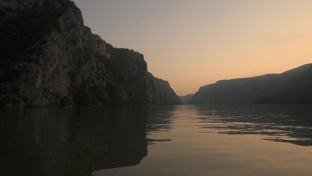 Danube Gorges (Cazanele Dunarii in Romanian language) view from a boat during a beautiful summer sunrise. Cruise on Danube River, 4k video. Landmarks of Romania.