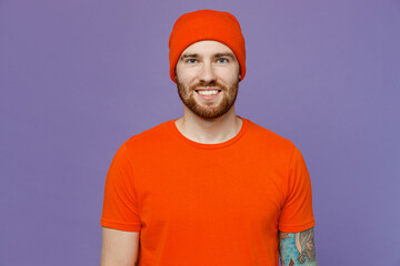Young smiling stylish calm confident, student stylish european man 20s wear red hat t-shirt looking camera isolated on plain pastel light purple background studio portrait. People lifestyle concept