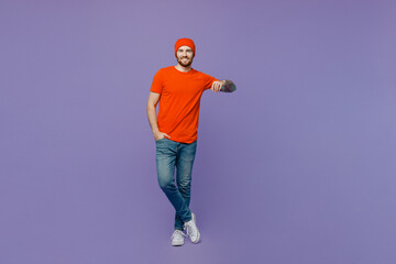 Full body young smiling european man 20s he wear red hat t-shirt hold place for promo copy space advert area isolated on plain pastel light purple background studio portrait. People lifestyle concept.
