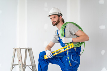 Portrait of male worker professional electrician in uniform installing electrical outlet in apartment after renovation work. Manual work, maintenance, occupation concept. Side view