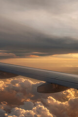 Vertical view of an airplane flying above the clouds against a beautiful sunset