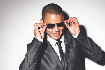 Fashion, model from Brazil and sunglasses in a studio in a luxury business suit looking cool. Attractive man on set with a white background and happy smile modeling for a rich designer glasses brand