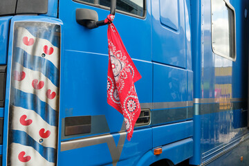 Red farmer handkerchief as a farmers protests symbol in The Netherlands attached to a blue truck. Farmers in the Netherlands protesting against forced shrinking of livestock because of CO2 emissions.  - obrazy, fototapety, plakaty