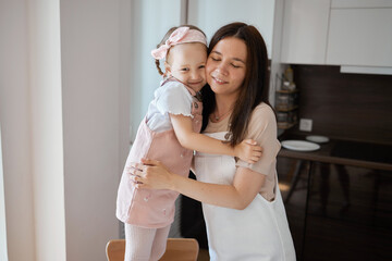 A happy loving family is preparing a bakery together. Mother and daughter cook food, have fun in...