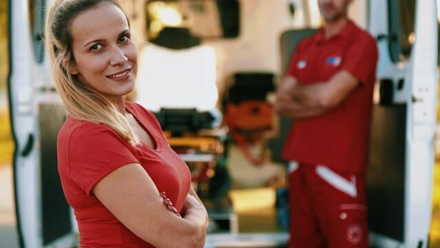 Portrait of a female EMS paramedic  standing in front of the ambulance and looking at camera