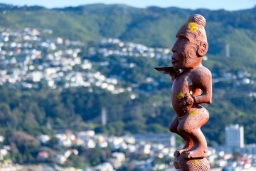 Māori pou intricate carved cultural monument sculpture on popular tourism landmark Mt Vic with residential houses in Capital Wellington, New Zealand Aotearoa, close up