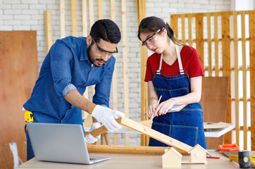 Indian professional male engineer foreman labor worker using laptop computer meeting discussing with cheerful female colleague wear safety goggles writing note on paper clipboard in construction site