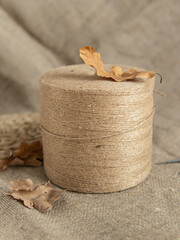 Bobbin of jute twine threads and autumn leaves. Natural