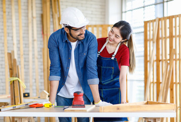 Asian professional female and Indian bearded male engineer architect foreman labor worker lover couple wear safety hard helmet jeans apron and gloves standing smiling together in construction site