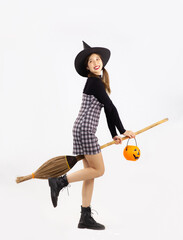 Halloween theme, young asian woman in black dress, boots, witch hat holding broom and carrying...
