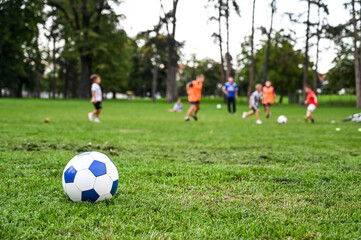 Children playing football on school terrain. Ball in foreground while boys are playing in the...