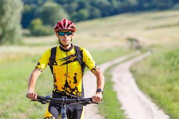 A cyclist in sportswear poses with his mountain bike