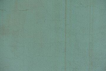 Weathered dusty mint colored painted wall with cracks texture