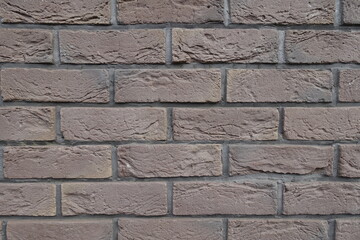 Uneven surface of dark chocolate brown brick wall