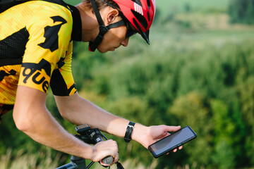 Happy male cyclist sending a text message on his mobile phone. Image of a cyclist on a mountain...