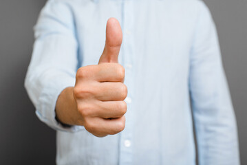 Close-up man showing like gesture, non-verbal thumbs up sign, ok symbol, agreement