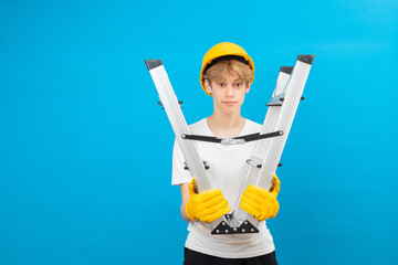 Young repairman teen in white t-shirt and gloves with yellow helmet in head, holding ladder in...