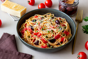Spaghetti pasta Alla Puttanesca with capers, Kalamata olives, cheese, tomatoes and anchovies. Italian food.