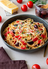 Spaghetti pasta Alla Puttanesca with capers, Kalamata olives, cheese, tomatoes and anchovies. Italian food.