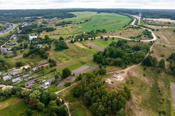 Fototapeta na wymiar aerial panoramic view of green village with houses, barns and gravel road in forest