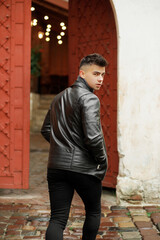 Obraz premium Stylish man with a fashionable hairstyle in a leather jacket posing on the street in motion.