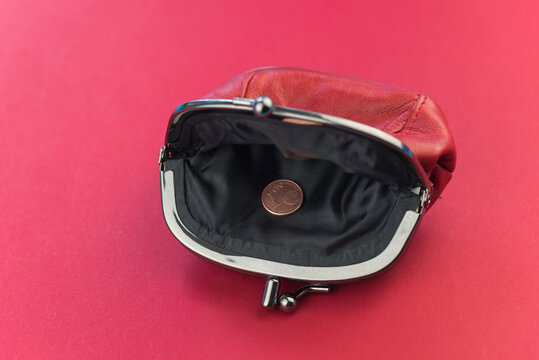 A red wallet with only one coin in it on a red background as a term for poverty and being broke