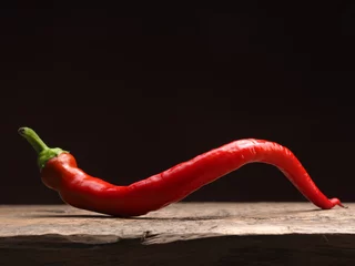 Fotobehang Chili Pepers Spicy organic red chili pepper on a rustic wooden table, food ingredients, space for text, dark background  © Andreas Berheide