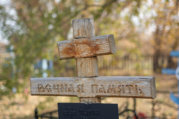 Old wooden cross in the cemetery with the inscription Eternal Memory in Russian