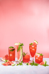 Different elegant glasses with watermelon cocktail. Splash, splatter, water drops on the pink background