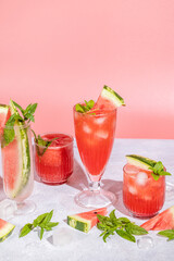 Different elegant glasses with watermelon cocktail. Splash, splatter, water drops on the pink background