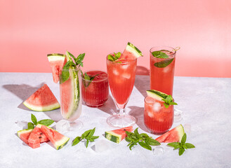 Different elegant glasses with watermelon cocktail. Splash, splatter, water drops on the pink background